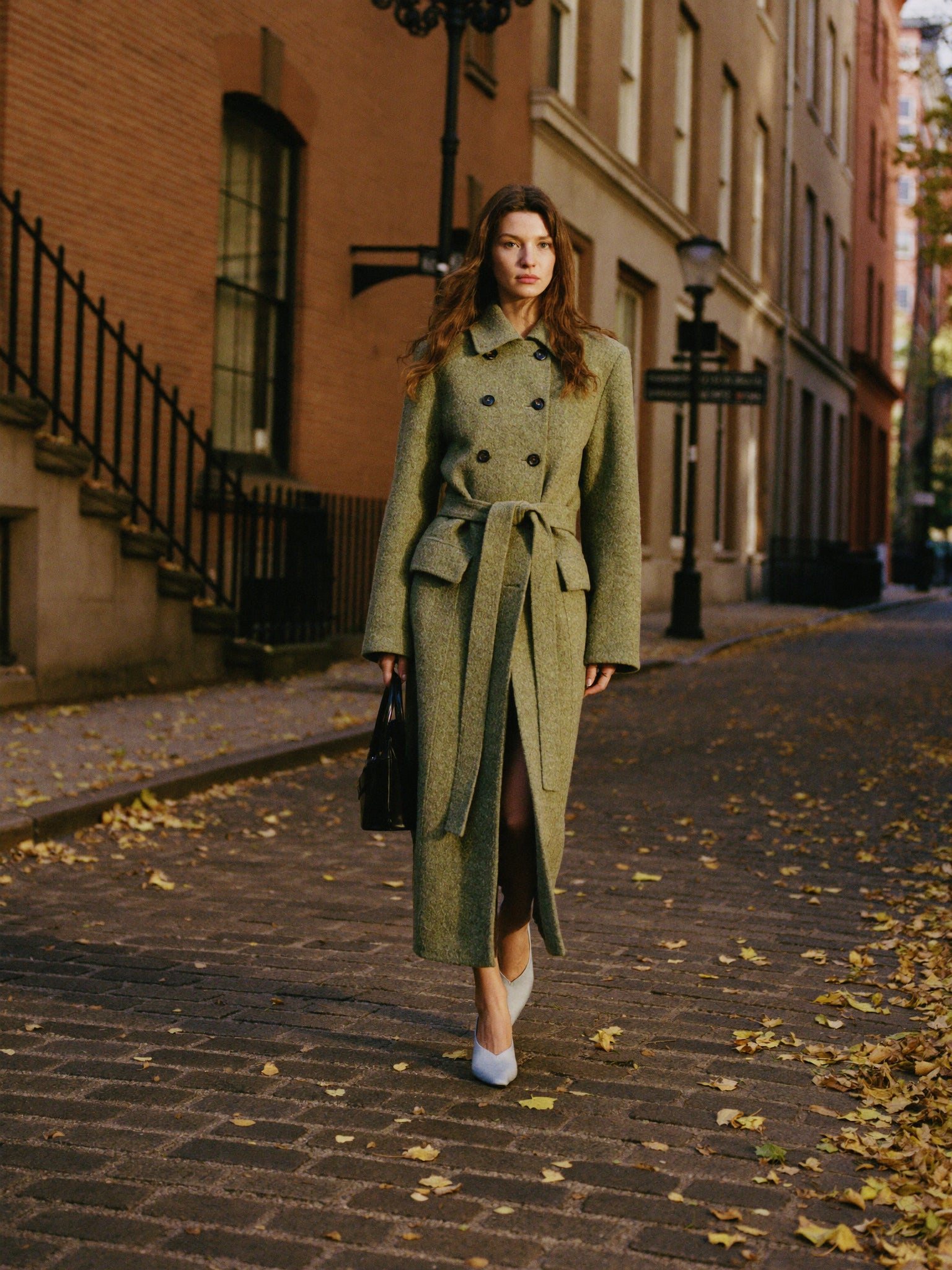 A woman in a camel coat walking on an autumn London street