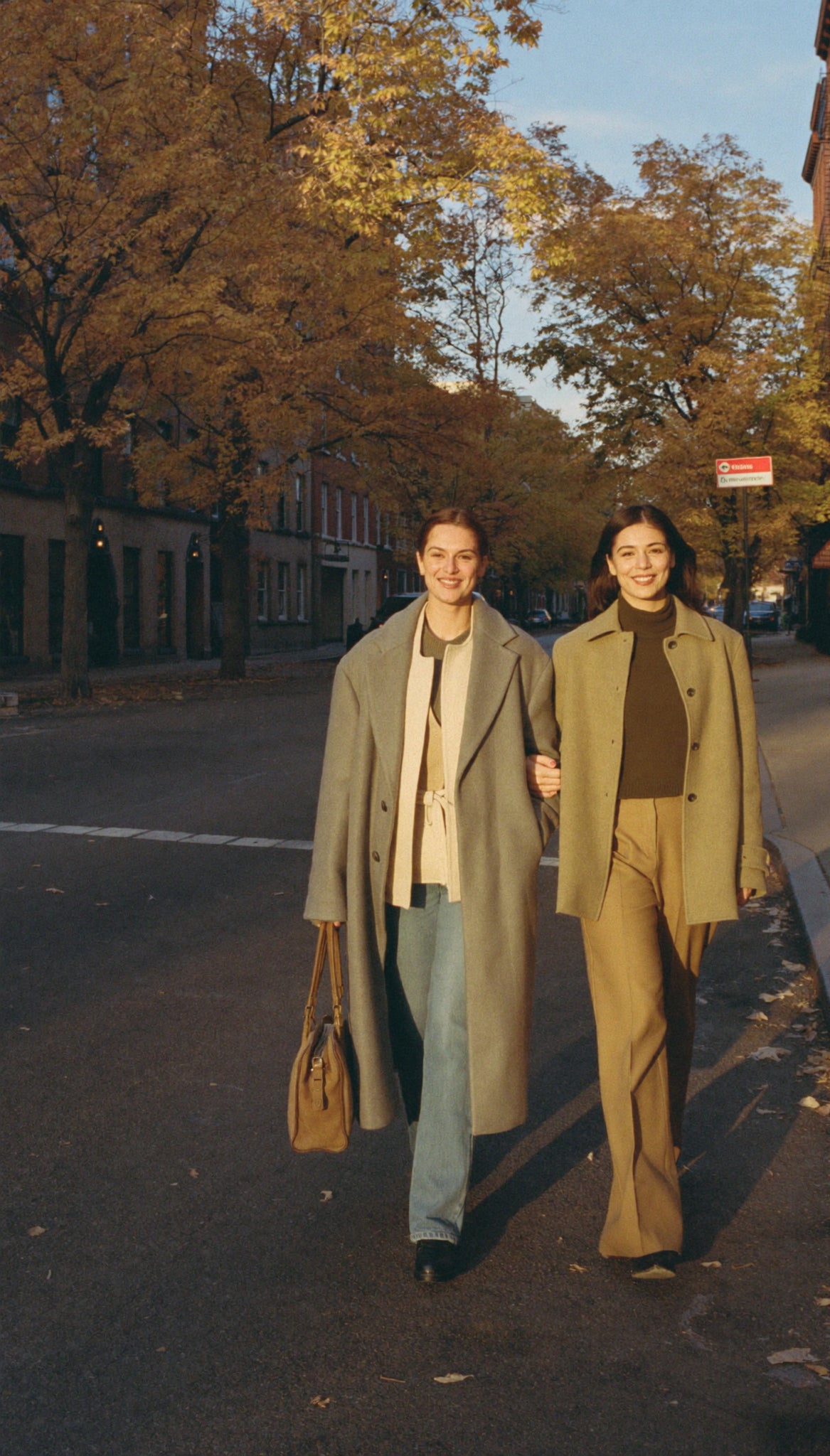 Two friends walking together on an autumn city street, styled in Rose Weston outerwear and knitwear